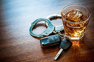 Car Keys & Handcuffs Laying Next To A Glass Of Alcohol