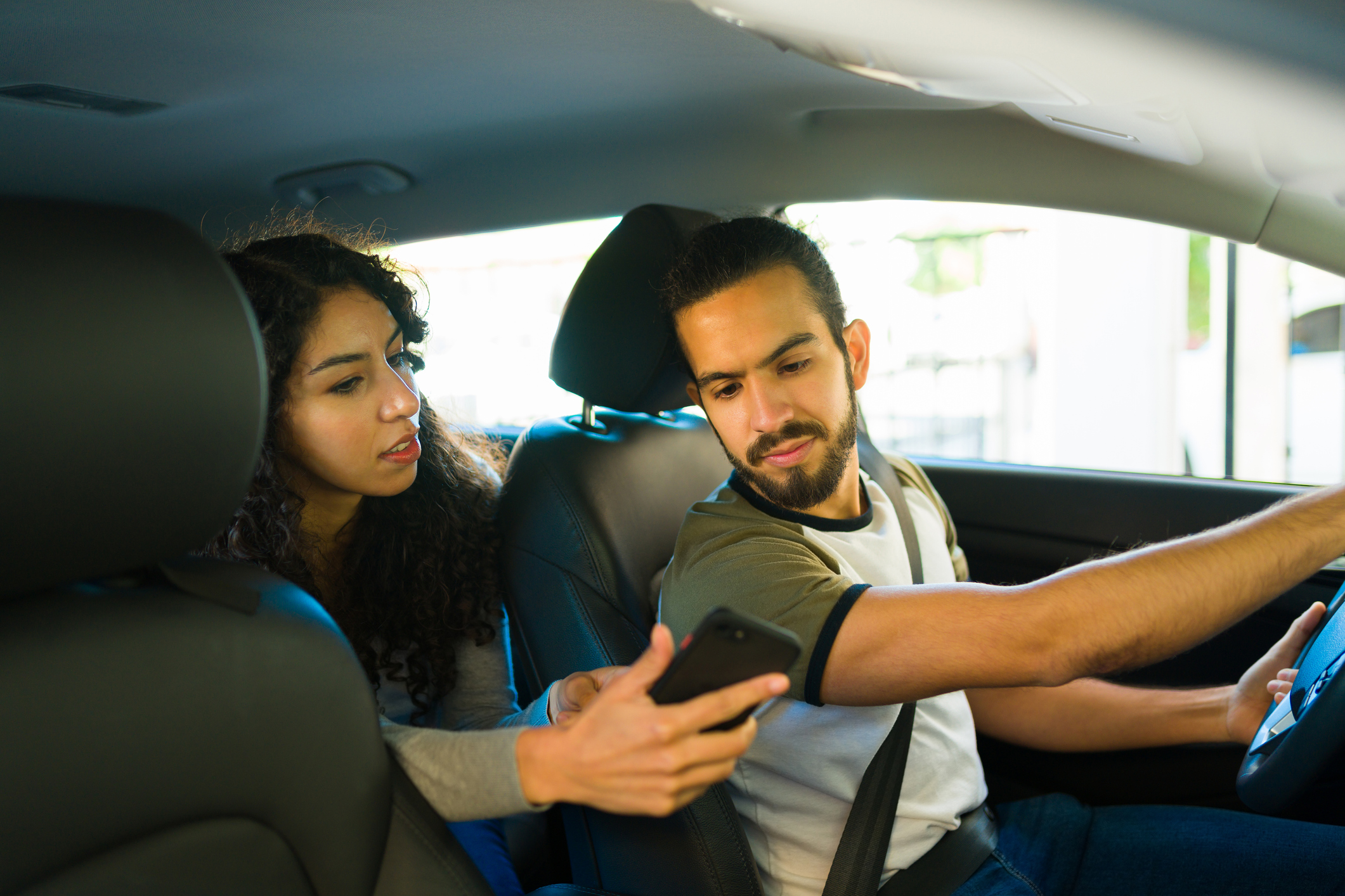 A Millbrook rideshare driver looks at the passenger’s phone as she shows him directions to her destination.