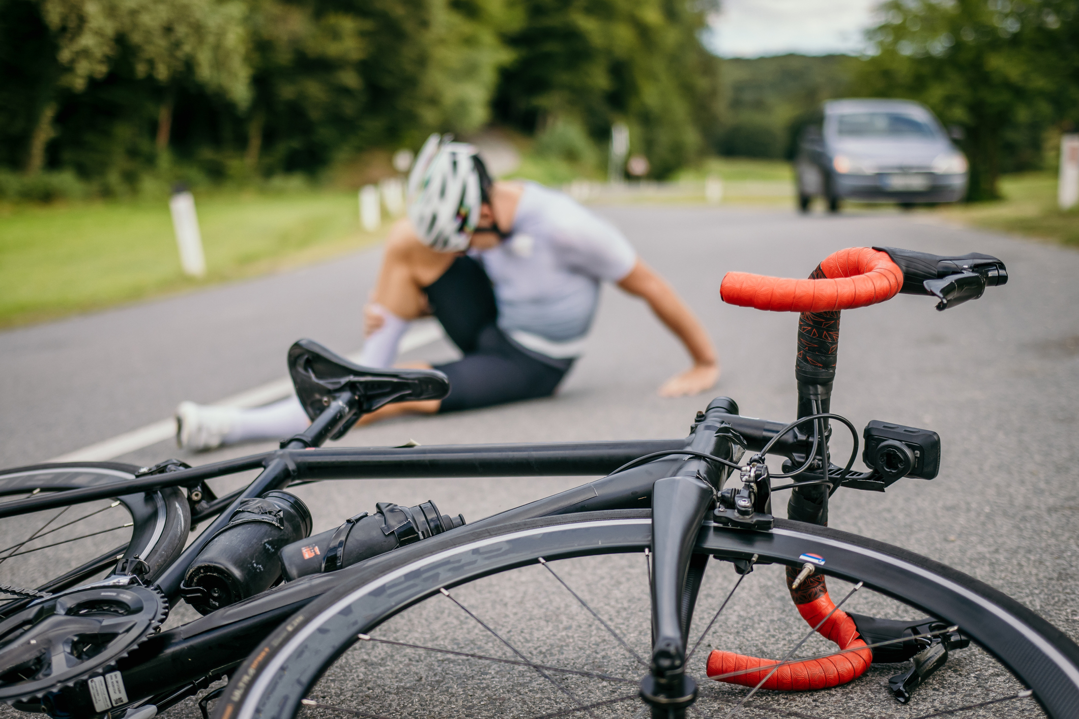 The victim of a Millbrook bicycle accident sits on the ground in pain next to his bike.